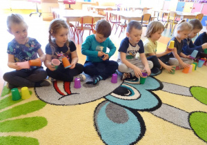 Dzieci bawią się kolorowymi kubkami.
